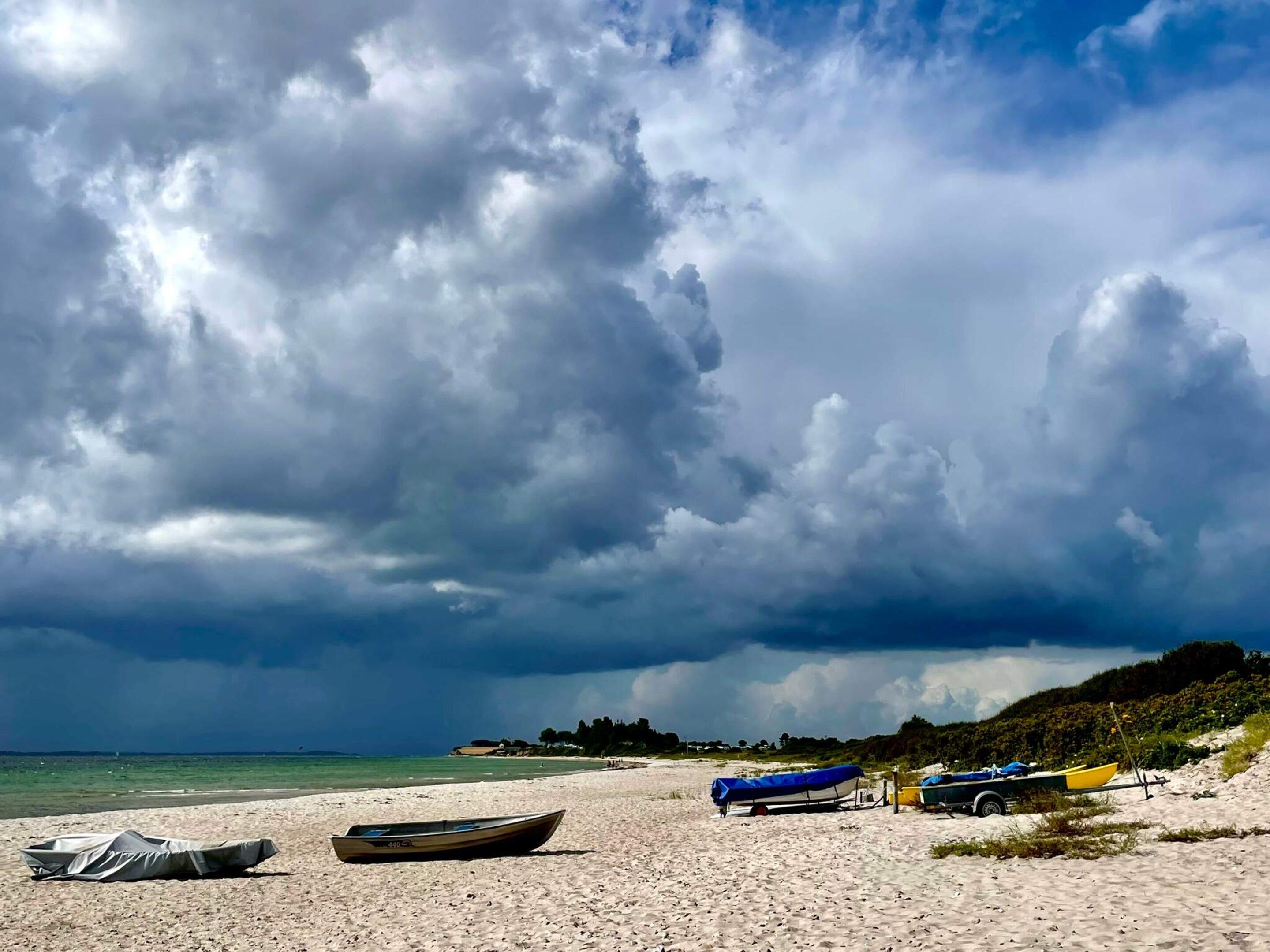 A beach with boats and a trailer.