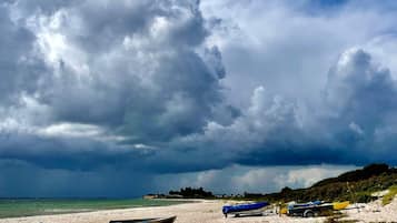 A beach with boats and a trailer.