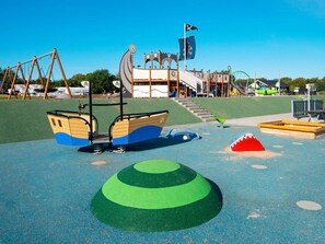 A playground with a slide, swings, and a climbing structure. - 5 Star Holiday Home in Sydals (Sydals)