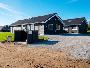 A modern two-story house with a gravel driveway and a covered garage.