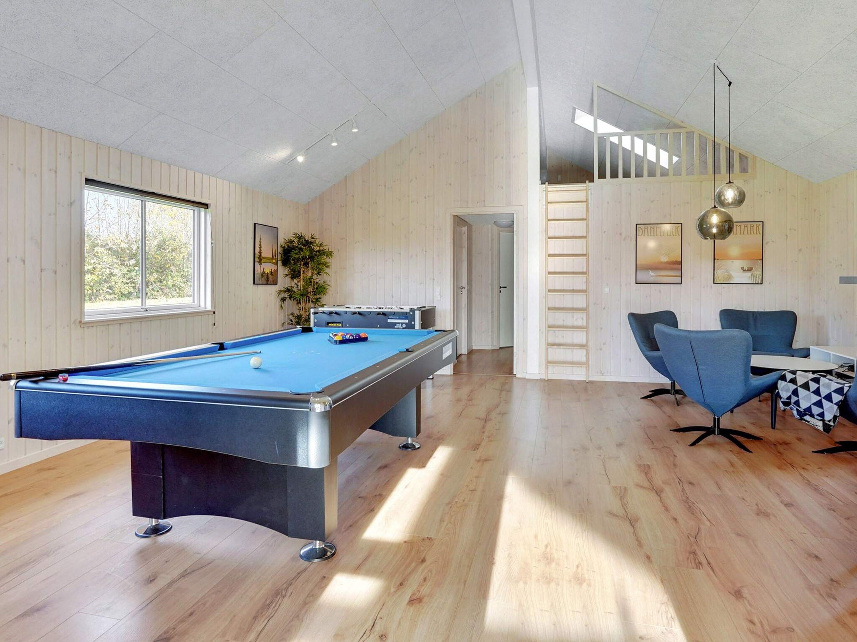 A pool table in a room with wooden walls and a high ceiling.