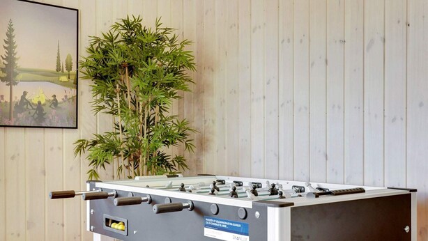 A foosball table with a label indicating it is from SKANLUX, set against a wooden wall with a framed picture of a landscape. - 5 Star Holiday Home in Sydals (Sydals)
