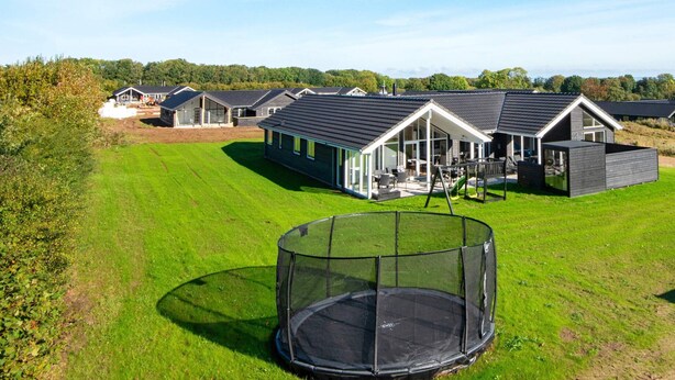 Ett bostadsområde med moderna hus, en välskött gräsmatta och en studsmatta.