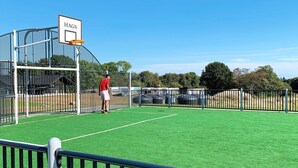En basketplan med ett nät där det står ”HAGS” och en person som står nära korgen.