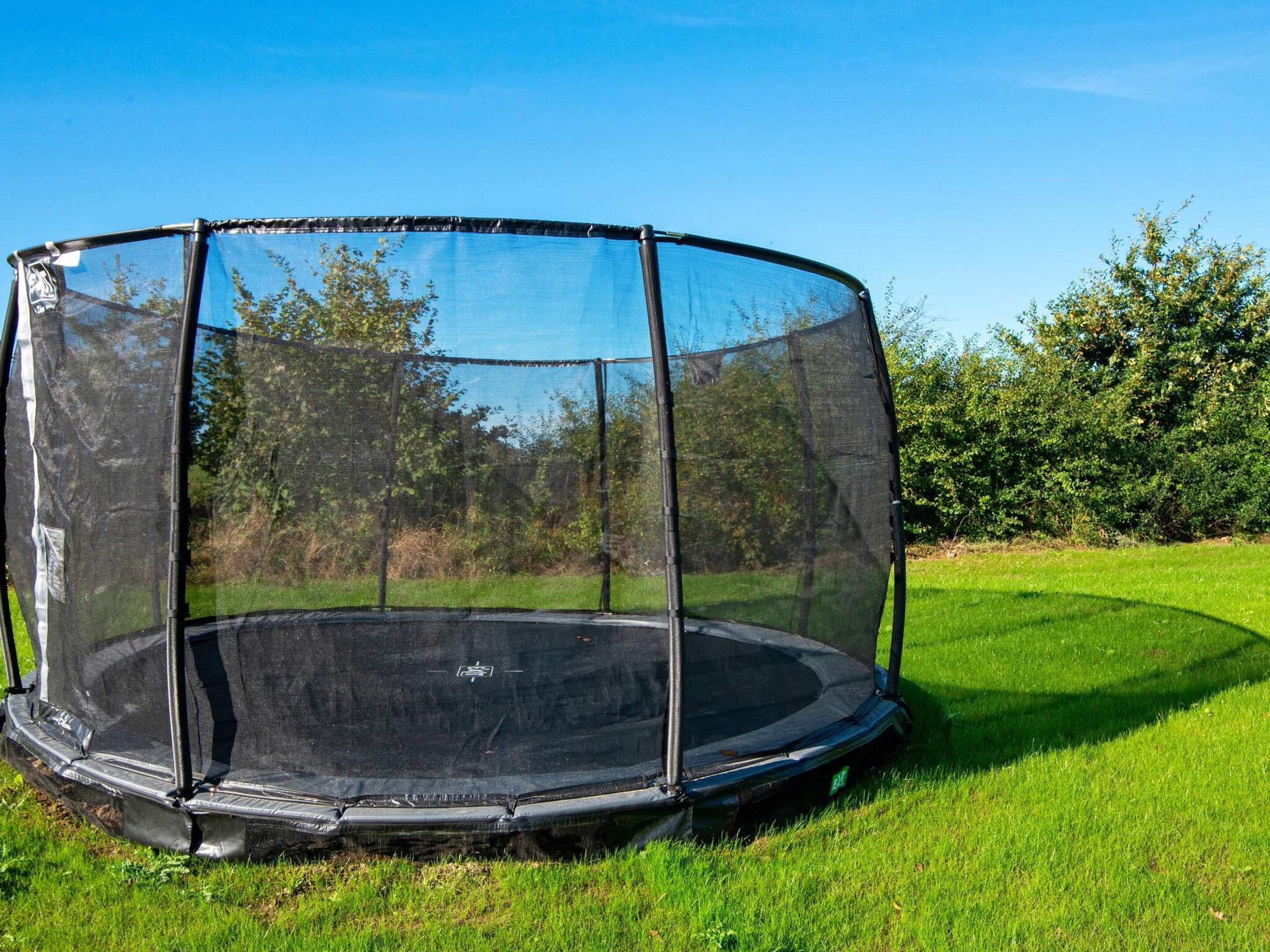A trampoline with a safety net enclosure in a grassy area.