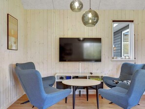 A living room with two blue armchairs, a round table, a flat-screen TV, wooden panel walls, and a window with a view. - 5 Star Holiday Home in Sydals (Sydals)