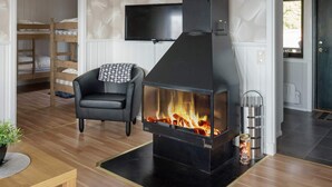 A cozy room with a fireplace, a television, a bunk bed, and a chair. - 6 Person Holiday Home in Kopparberg (Kopparberg)