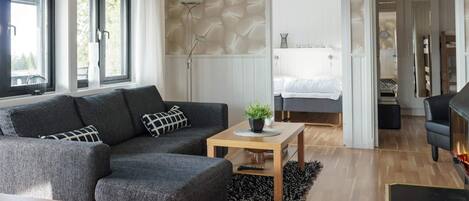 Una sala moderna con un sofá modular gris, una mesa de centro de madera y un tapete negro.