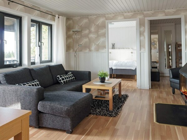 A modern living room with a grey sectional sofa, a wooden coffee table, and a black rug. - 6 Person Holiday Home in Kopparberg (Kopparberg)