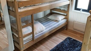 A bunk bed with a window above, wooden flooring, and a blue rug. - 6 Person Holiday Home in Kopparberg (Kopparberg)