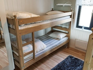 A bunk bed with a window above, wooden flooring, and a blue rug. - 6 Person Holiday Home in Kopparberg (Kopparberg)