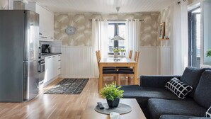 A modern living room with a sofa, a coffee table, and a dining area with a table and chairs. - 6 Person Holiday Home in Kopparberg (Kopparberg)