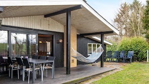 A modern outdoor dining area with a wooden deck, black chairs, and a hammock. - 10 Person Holiday Home in Ronde (Ronde)