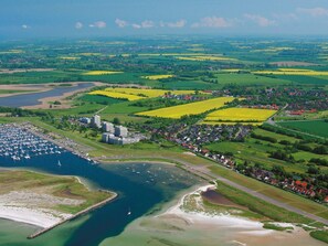 An aerial view of a coastal town with a marina, residential areas, and agricultural fields. - 5 Star Holiday Home in Wendtorf (Wendtorf)