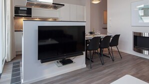 A modern kitchen with a built-in microwave, oven, and a large flat-screen TV mounted on the wall.