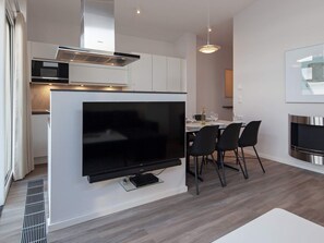 A modern kitchen with a built-in microwave, oven, and a large flat-screen TV mounted on the wall.