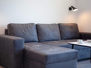 A modern, dark-colored sofa with a white cup and saucer on a small table beside it. - 5 Star Holiday Home in Wendtorf (Wendtorf)