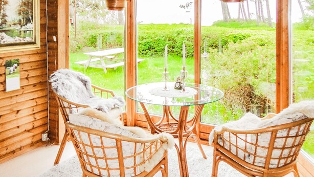 A cozy room with wicker chairs, a glass table, and a view of a garden through large windows. - 6 Person Holiday Home in Gorlev (Gørlev)