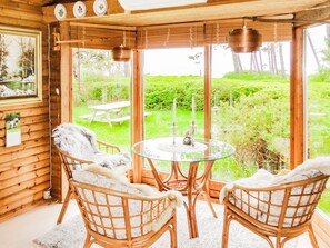 A cozy room with wicker chairs, a glass table, and a view of a garden through large windows. - 6 Person Holiday Home in Gorlev (Gørlev)
