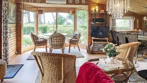A cozy cabin interior with a dining area, seating, a TV, and a large window offering a view of the outdoors. - 6 Person Holiday Home in Gorlev (Gørlev)