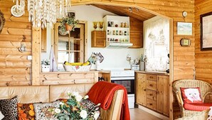 A cozy log cabin interior with a wooden dining area, a kitchen with wooden cabinets, and a living room with a sofa and decorative pillows. - 6 Person Holiday Home in Gorlev (Gørlev)