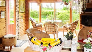 A cozy room with wicker furniture, a wicker basket with a yellow package, a small table with a glass top, and a potted plant. - 6 Person Holiday Home in Gorlev (Gørlev)