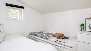 Ett sovrum med en säng, en madrass, ett nattduksbord med en lampa och ett fönster.