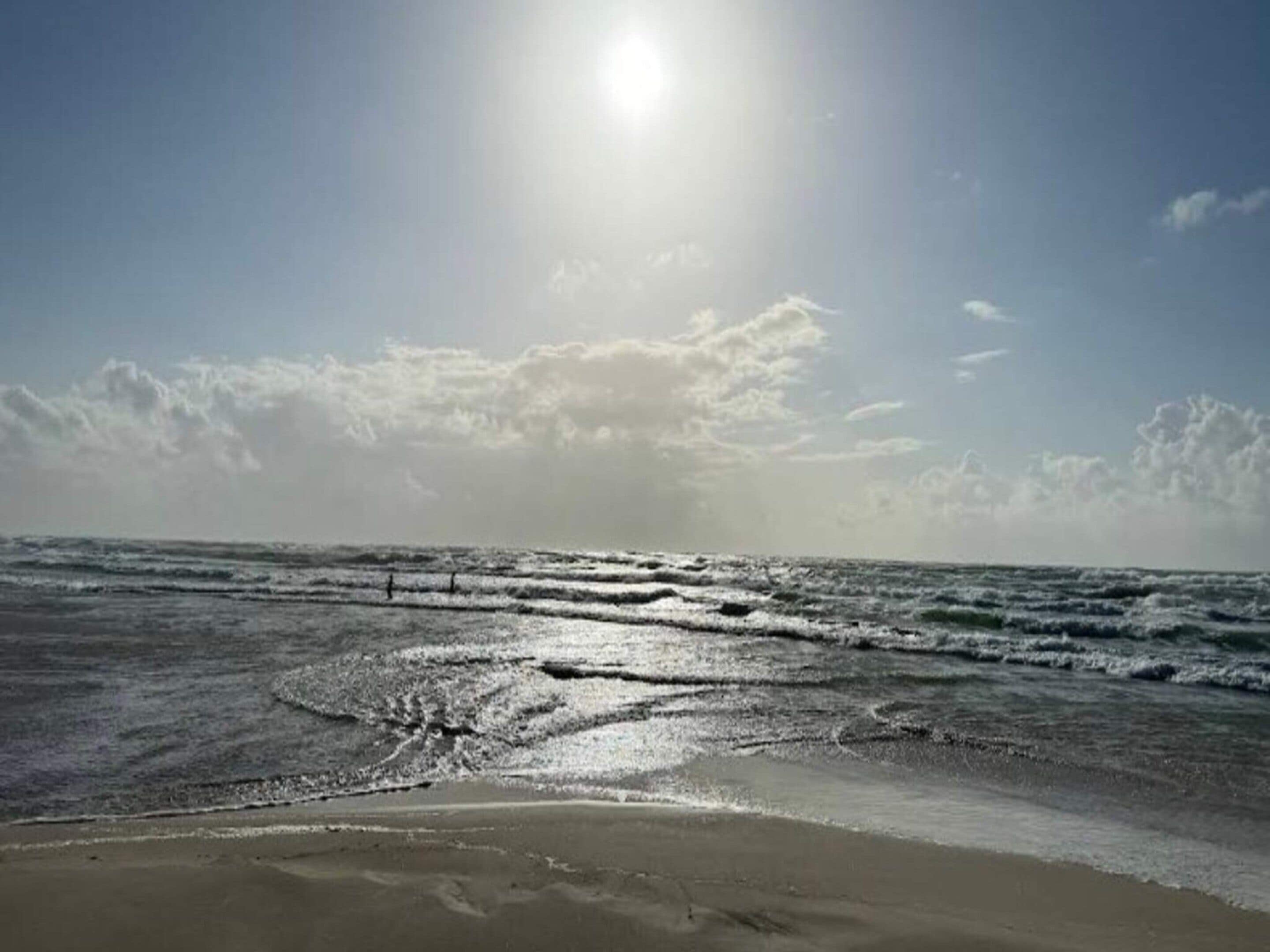 A beach with waves and a clear sky.