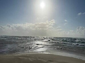A beach with waves and a clear sky.