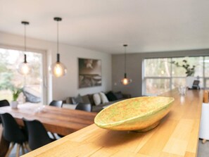 A modern dining area with a wooden table, chairs, pendant lighting, and a large ceramic bowl. - 6 Person Holiday Home in Blokhus (Blokhus)