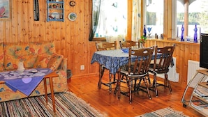 A cozy room with wooden walls, a dining table with chairs, a sofa, and a television. - 2 Person Holiday Home in Bengtsfors-by Traum (Bengtsfors)