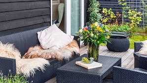 A patio with wicker furniture, a book, and a vase with flowers. - 5 Star Holiday Home in Vaeggerlose (Vaeggerlose)