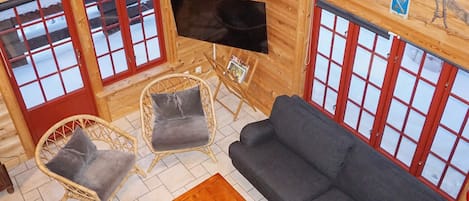 A log cabin interior with a sofa, chairs, a coffee table, and a flat-screen TV.