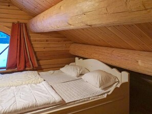 A wooden cabin room with a single bed, a window with curtains, and a sloped ceiling. - 4 Star Holiday Home in Salen (Salen)