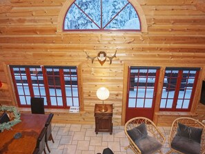 A log cabin interior with a dining area, two windows with red frames, a wall-mounted light fixture, and a decorative antler. - 4 Star Holiday Home in Salen (Salen)