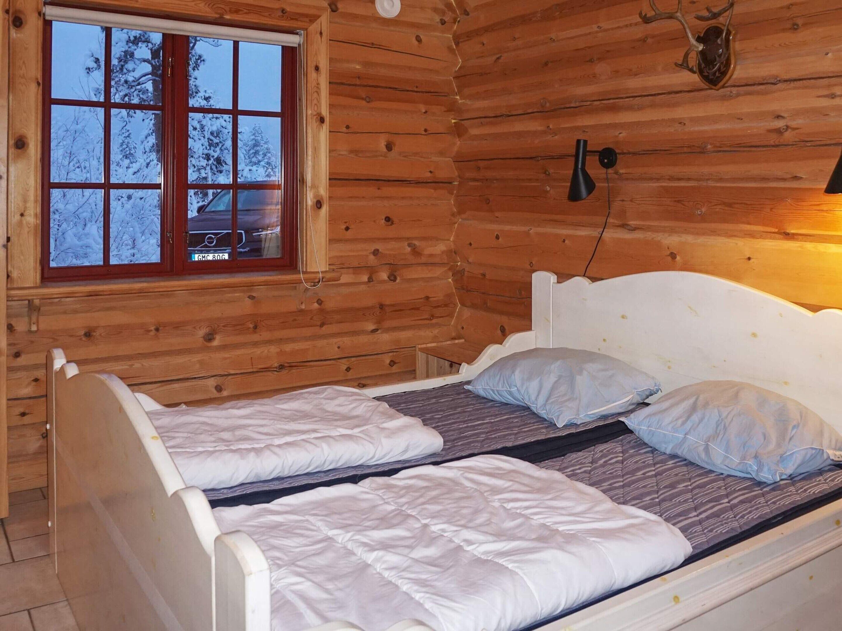 A wooden cabin with a bed featuring two single beds and a headboard.