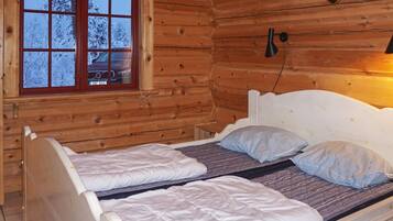 A wooden cabin with a bed featuring two single beds and a headboard.