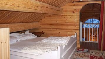A wooden interior with a bed, a small table, and a window with bars.