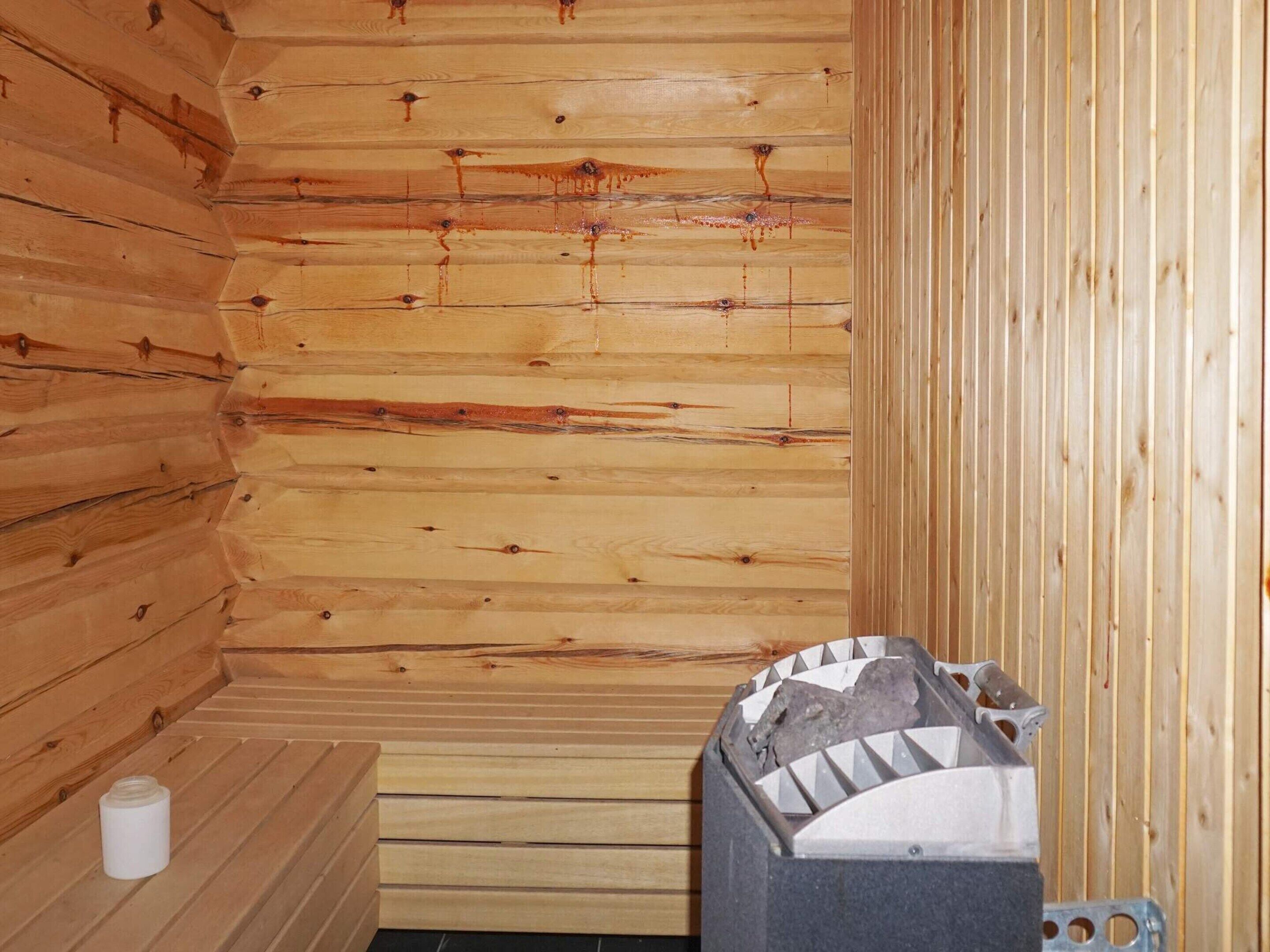 Ein Holzsaunaraum mit einer Sitzbank und einer Saunaduschbrause.