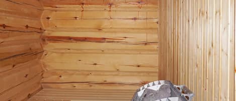 A wooden sauna room with a bench and a sauna head.
