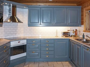 A kitchen with blue cabinets, a stainless steel range hood, a built-in oven, and a countertop with a toaster and a coffee maker. - 4 Star Holiday Home in Salen (Salen)