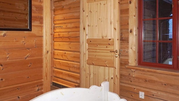 A wooden cabin room with a bed, a door, and a window. - 4 Star Holiday Home in Salen (Salen)