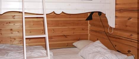 A bunk bed with a ladder, white bedding, and a wooden cabin interior.