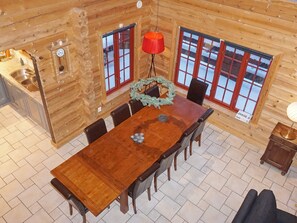 A wooden cabin interior with a dining table, chairs, a clock, and a window with a view of snow. - 4 Star Holiday Home in Salen (Salen)