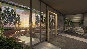 Un espacio interior moderno con paredes de vidrio, un sendero curvo y plantas en macetas.