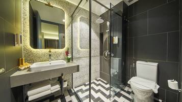 Un baño moderno con cabina de ducha de vidrio, un lavabo con espejo y un inodoro.