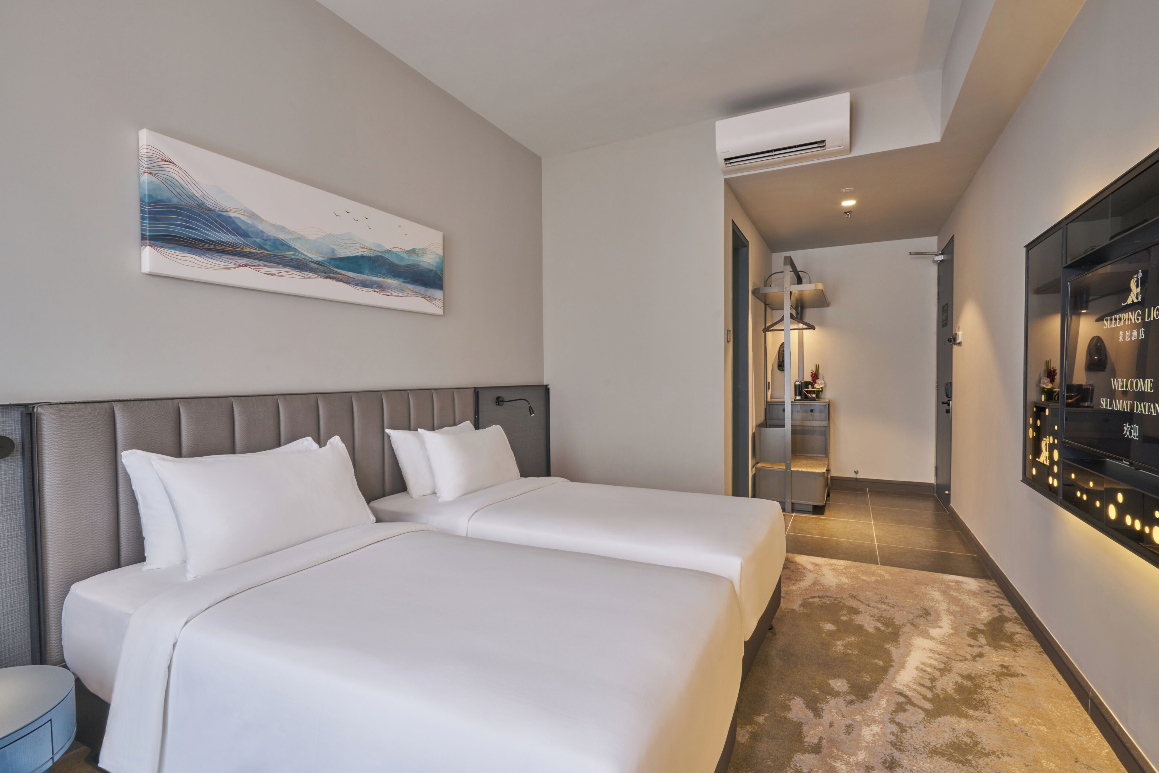 A hotel room with two beds, a large abstract painting, an air conditioning unit, and a hallway with a welcome sign.