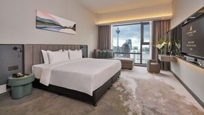 Habitación de hotel moderna con una cama grande, televisión, vistas a la ciudad y un cuadro en la pared.
