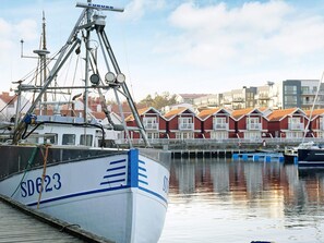 A harbor with a white boat docked, a red-roofed building in the background, and a clear sky.