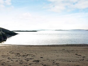 A beach with footprints in the sand and a calm sea. - 6 Person Holiday Home in Stromstad (Stromstad)